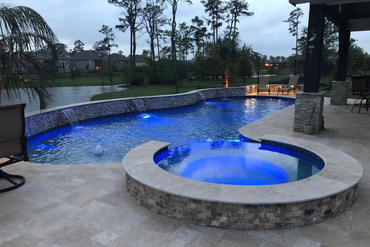 Custom pool with natural stone finish featuring ambient LED lighting and water features